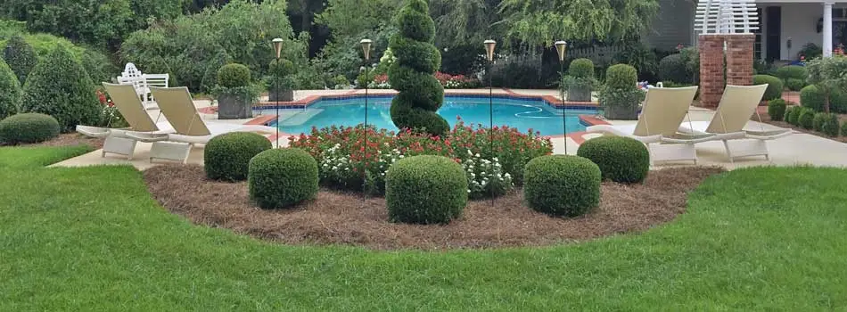 Mowing and landscape maintenance around a pool with beautifully trimmed shrubs in Wrens, GA.